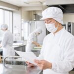 清潔な施設厨房で調理工程を確認する調理師