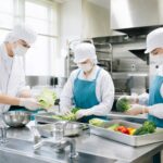 清潔な給食厨房で調理をする調理師のチーム